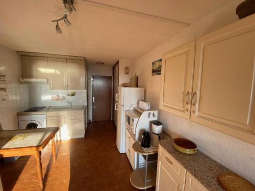 une cuisine avec un réfrigérateur blanc et une table dans l'établissement Studio en Bord de Mer, 4 Couchages, Parking Privé, Près des Commodités et Parc Aqualand - FR-1-81-577, au Barcarès