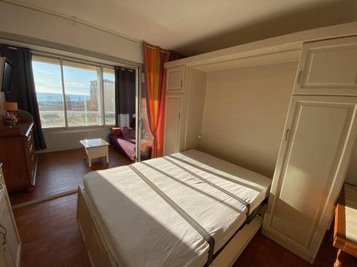 une chambre avec un lit et une grande fenêtre dans l'établissement Studio en Bord de Mer, 4 Couchages, Parking Privé, Près des Commodités et Parc Aqualand - FR-1-81-577, au Barcarès