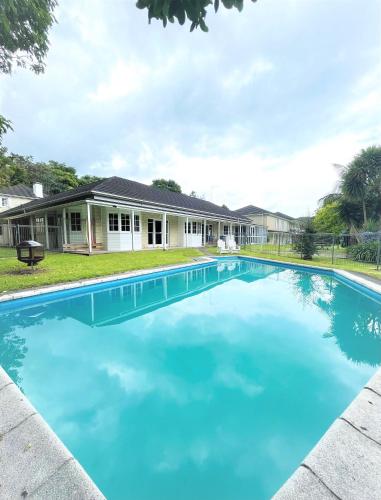 a large blue swimming pool in front of a house at Discovery Settlers Hotel in Whangarei
