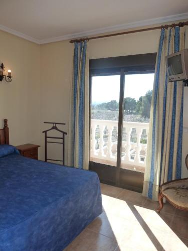 a bedroom with a blue bed and a large window at Hotel Rural Miguel Rosi in Huércal-Overa