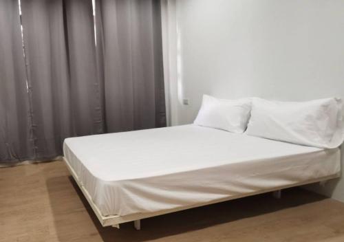 1 cama con sábanas blancas y almohadas en una habitación en GO INN Pattaya en Pattaya North