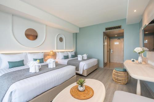 a hotel room with two beds and a table at Cosy Beach Hotel - SHA Extra Plus in Pattaya South