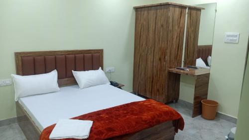 a bedroom with a large bed and a wooden cabinet at Shagun Banquet and Hotel in Gwalior
