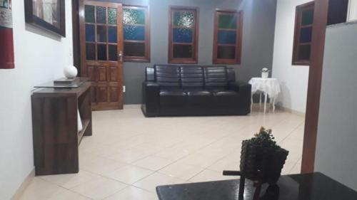 ein Wohnzimmer mit einem schwarzen Ledersofa und einem Tisch in der Unterkunft Pousada Paraiso Guarapari in Guarapari