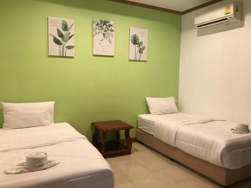 two beds in a room with green walls at Kanokwan Guesthouse in Ko Tao