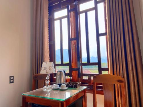 a table with a lamp on it next to a window at The Hill Villas in Phong Nha
