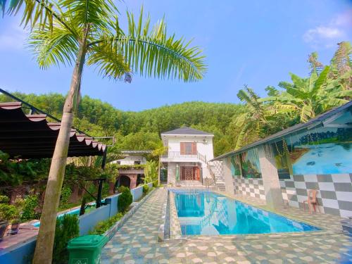 a villa with a swimming pool and a palm tree at The Hill Villas in Phong Nha