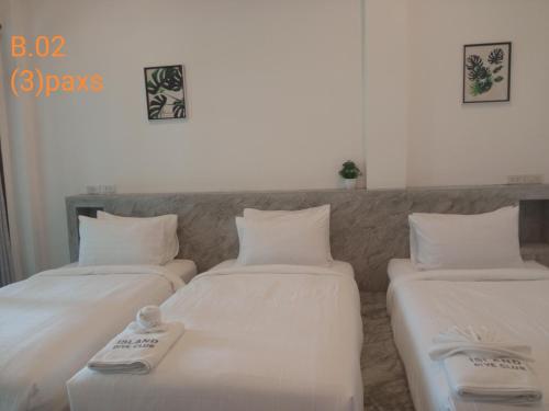 two beds in a room with white sheets and towels at Island Dive Club in Koh Tao