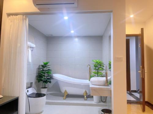 uma casa de banho com banheira e 2 vasos de plantas em Rosy Hotel em Hanói