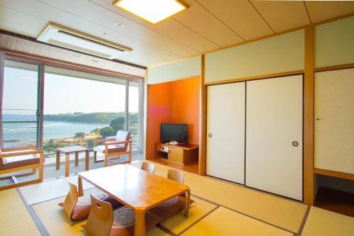 a living room with a table and a view of the ocean at Spa and Resort Hotel Solage Oita Hiji Beppuwan in Beppu