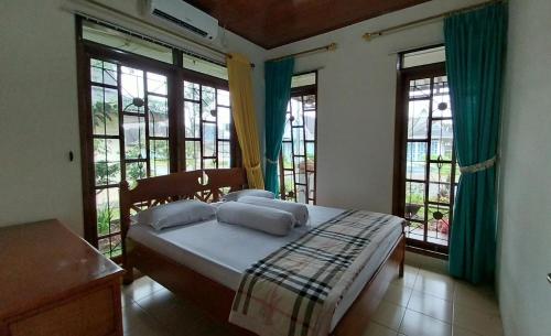 sypialnia z łóżkiem z niebieskimi zasłonami i oknami w obiekcie Pirerukafu Villa's - Villa Tipe Thailand di Kota Bunga Puncak w mieście Cimacan