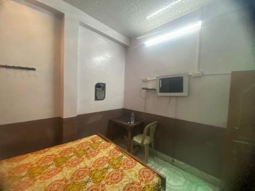 1 dormitorio con 1 cama, escritorio y TV en Yatri niwas home stay en Varanasi