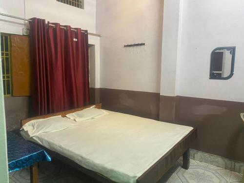 Cama pequeña en habitación con cortina roja en Yatri niwas home stay en Varanasi
