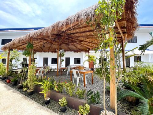 a patio with a wooden umbrella and tables and plants at MGH Alona Resort in Panglao