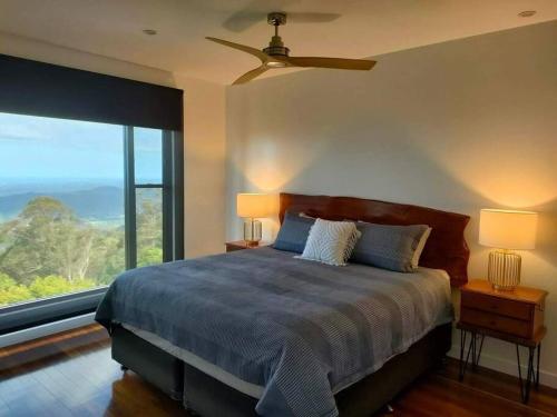 a bedroom with a bed and a large window at Coastline: Alpine Villa in Mount Tamborine