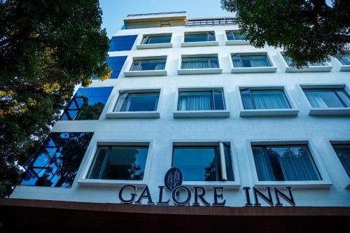 een wit gebouw met een Calore Inn bord erop bij Hotel Galore Inn in Mysore