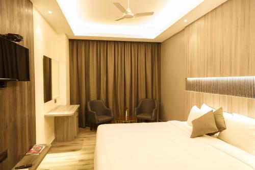 Habitación de hotel con cama y ventilador de techo. en Hotel Galore Inn, en Mysore