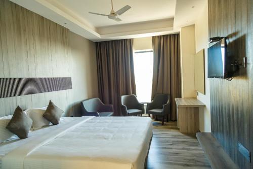 a hotel room with a bed and a flat screen tv at Hotel Galore Inn in Mysore