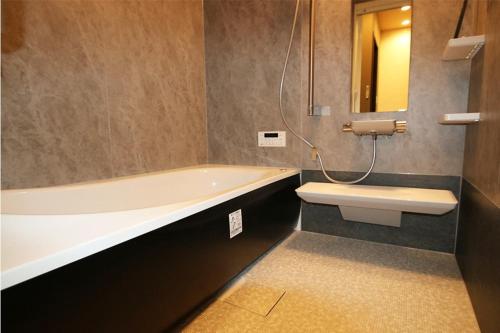 a bathroom with a tub and a toilet and a sink at Yadoya Matsumoto Honjo - Vacation STAY 13372v in Matsumoto