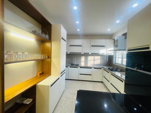 a kitchen with white cabinets and a black counter top at Woodlands Apartment- Fully furnished Luxury Apt in Jodhpur