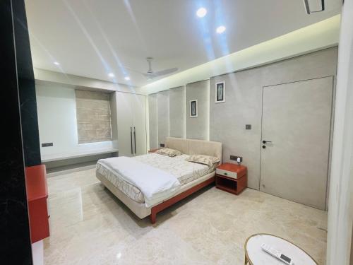 a bedroom with a bed and a table and a door at Woodlands Apartment- Fully furnished Luxury Apt in Jodhpur