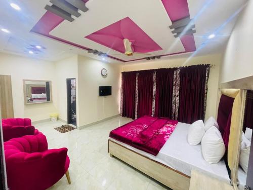 a bedroom with a bed and two red chairs at Royal palace hotel in Lahore