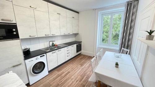 a white kitchen with a washing machine and a table at Villa Zentrum Haus Davos in Davos
