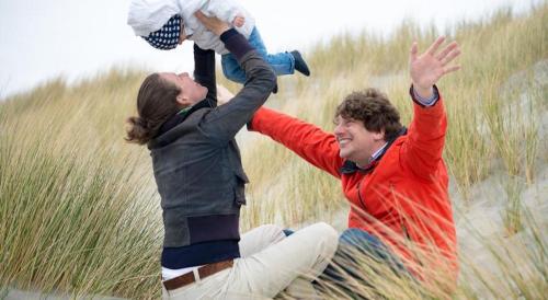a man and a woman are playing in the sand at 't STRANDHUYS en DE VUURTOREN, met eigen KEUKEN, ZONNIG TERRAS nabij DORP, DUINEN en STRAND, Incl verwarmd binnen ZWEMBAD in Hollum