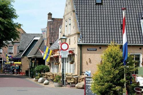 a street in a town with flags and a building at 't STRANDHUYS en DE VUURTOREN, met eigen KEUKEN, ZONNIG TERRAS nabij DORP, DUINEN en STRAND, Incl verwarmd binnen ZWEMBAD in Hollum