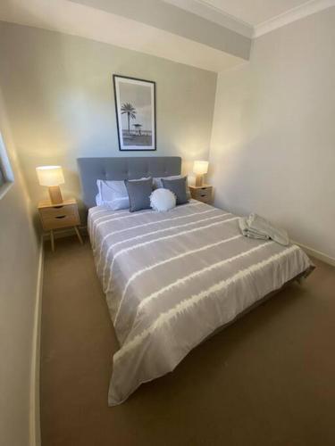 1 dormitorio con 1 cama blanca grande y 2 lámparas en Bright 1 Bedroom Joondalup Stay, en Perth