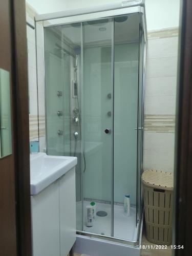 een badkamer met een glazen douche en een wastafel bij Certe notti in Taranto