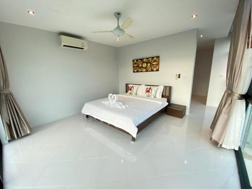 1 dormitorio blanco con 1 cama y ventilador de techo en 360 Degree Kamala Seaview Villa, en Kamala Beach