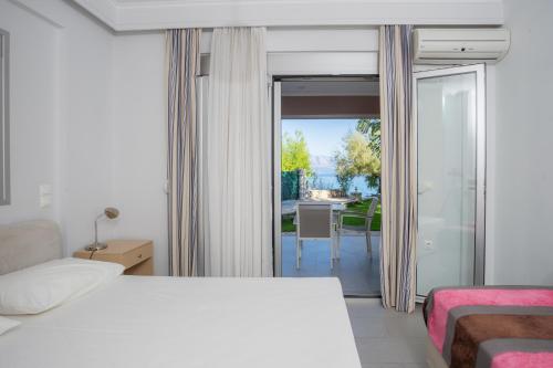 a bedroom with a bed and a sliding glass door at Lefkothea Apartments in Nikiana