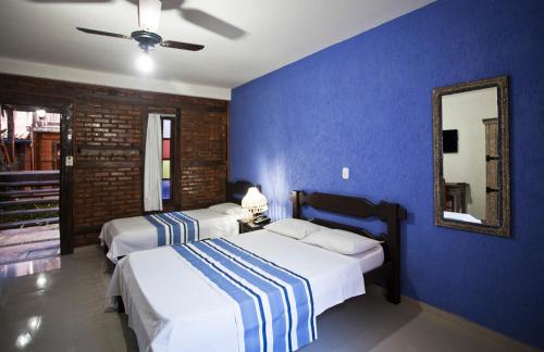 two beds in a bedroom with a blue wall at Quari Quara BY MN Hotéis in Rio das Ostras