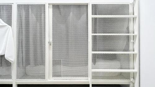 a white cabinet with white shelves next to a bed at Paknap Hostel in Nan