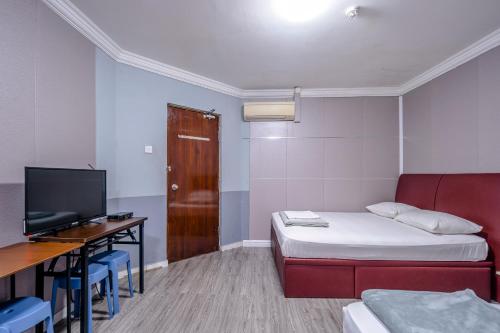 a room with a bed and a desk and a tv at K Hotel 8 in Singapore