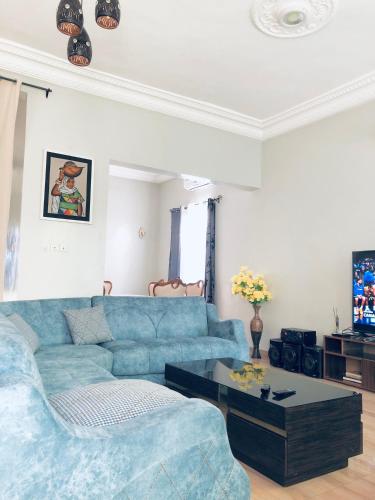 Sala de estar con sofá azul y mesa de centro en Superbe maison dans un quartier calme - Bénin, en Ekpé