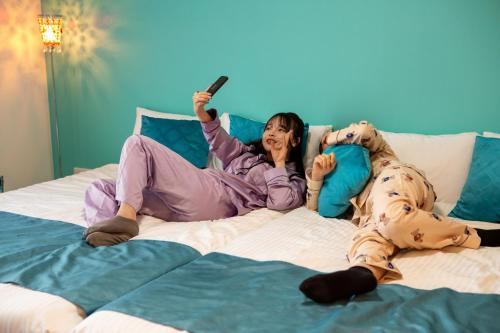 two women laying on a bed with a remote control at Japan Hinata Hotel 池下駅 1番出口 徒歩2分 1LDK 50平米 8名 in Nagoya