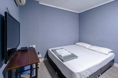 a bedroom with a bed and a table with a television at K Hotel 8 in Singapore