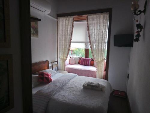 ein Schlafzimmer mit einem Bett und ein Fenster mit einem Sofa in der Unterkunft Birgi Hotel Saliha Hanim Tas Konak in Birgi