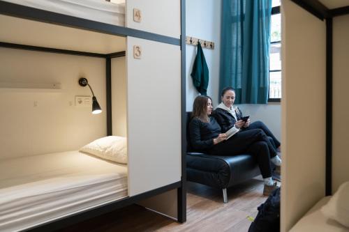 two women sitting in a room with a bed at Koba Hostel in Donostia-San Sebastián