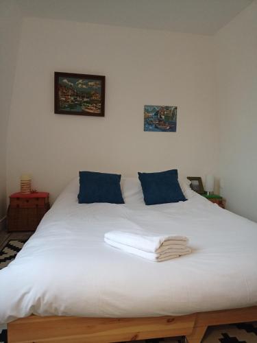 1 dormitorio con cama blanca y almohadas azules en La plus petite maison de pêcheur de Trouville-sur-mer, en Trouville-sur-Mer