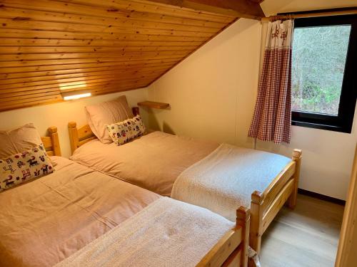 1 dormitorio con 2 camas y ventana en Gezellige familie chalet en Oizy