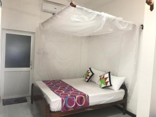 a small bedroom with a bed with a canopy at Jilan Homestay in Bentota