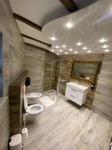 a bathroom with two sinks and a toilet and a shower at Motel pizzeria Antic's in Laktaši