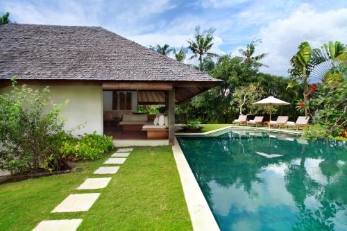 a villa with a swimming pool next to a house at Villas Sin Sin in Canggu