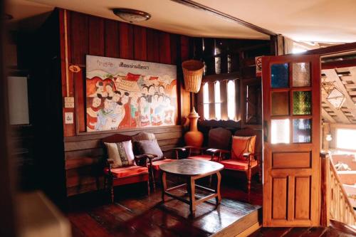 une chambre avec une table, des chaises et un tableau dans l'établissement เฮือนน่านนิทรา, à Nan