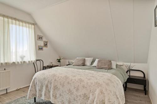 een witte slaapkamer met een bed en een raam bij Mooie twee-onder-een-kapwoning te Vlagtwedde in Vlagtwedde
