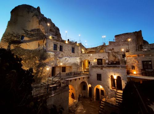 an old building with lights on the side of a mountain at Dervish Cave House & Restaurant in Göreme