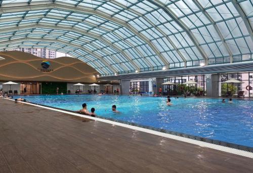 uma grande piscina com pessoas com um tecto de vidro em Apartment 1BR FL28th-Ruby-Vinhomes Ocean Park em Hanói